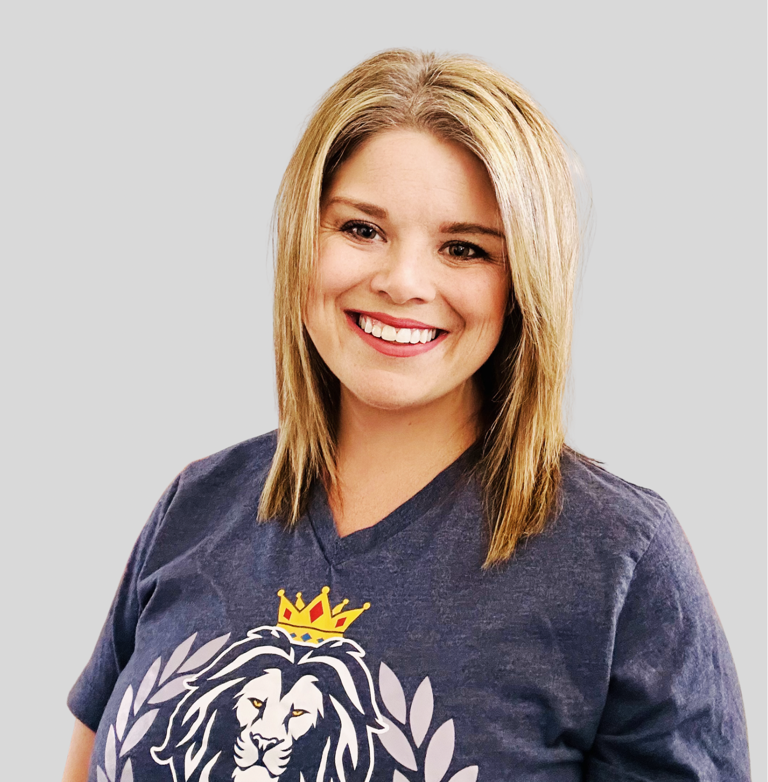 Woman is smiling and wearing a grey Manhattan Virtual Academy logo t-shirt.